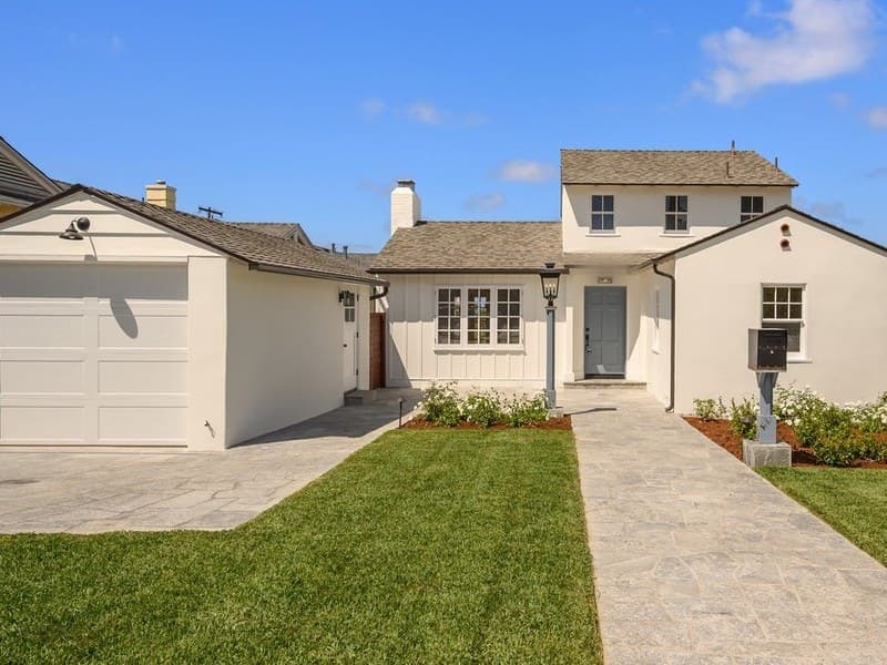 A white two-story La Jolla cottage with a blue front door, board-and-batten siding, and a flagstone walk, photographed in daylight before any holiday lighting