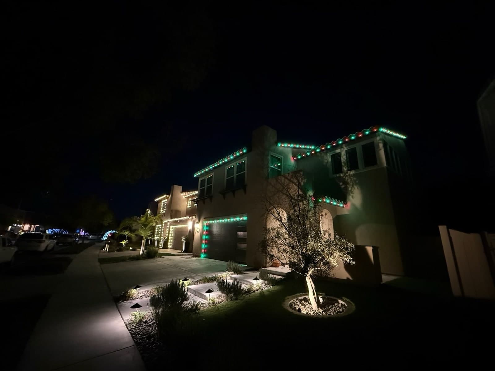 Red and green C9 Christmas lights tracing the tile roofline and garage of a two-story San Diego home at night